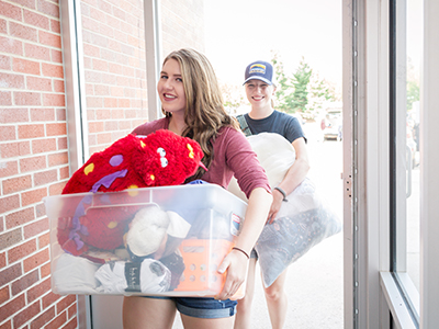 Two students carry in their items on Move-In day.